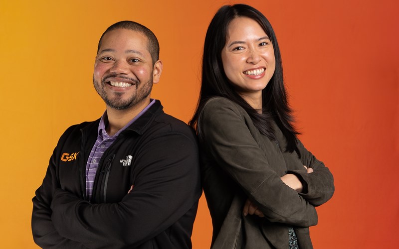two employees with an orange back drop.