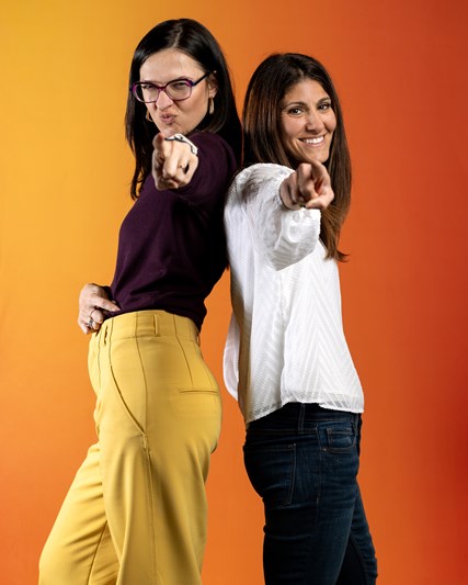 Two smiling employees posing with fingers pointed to the camera