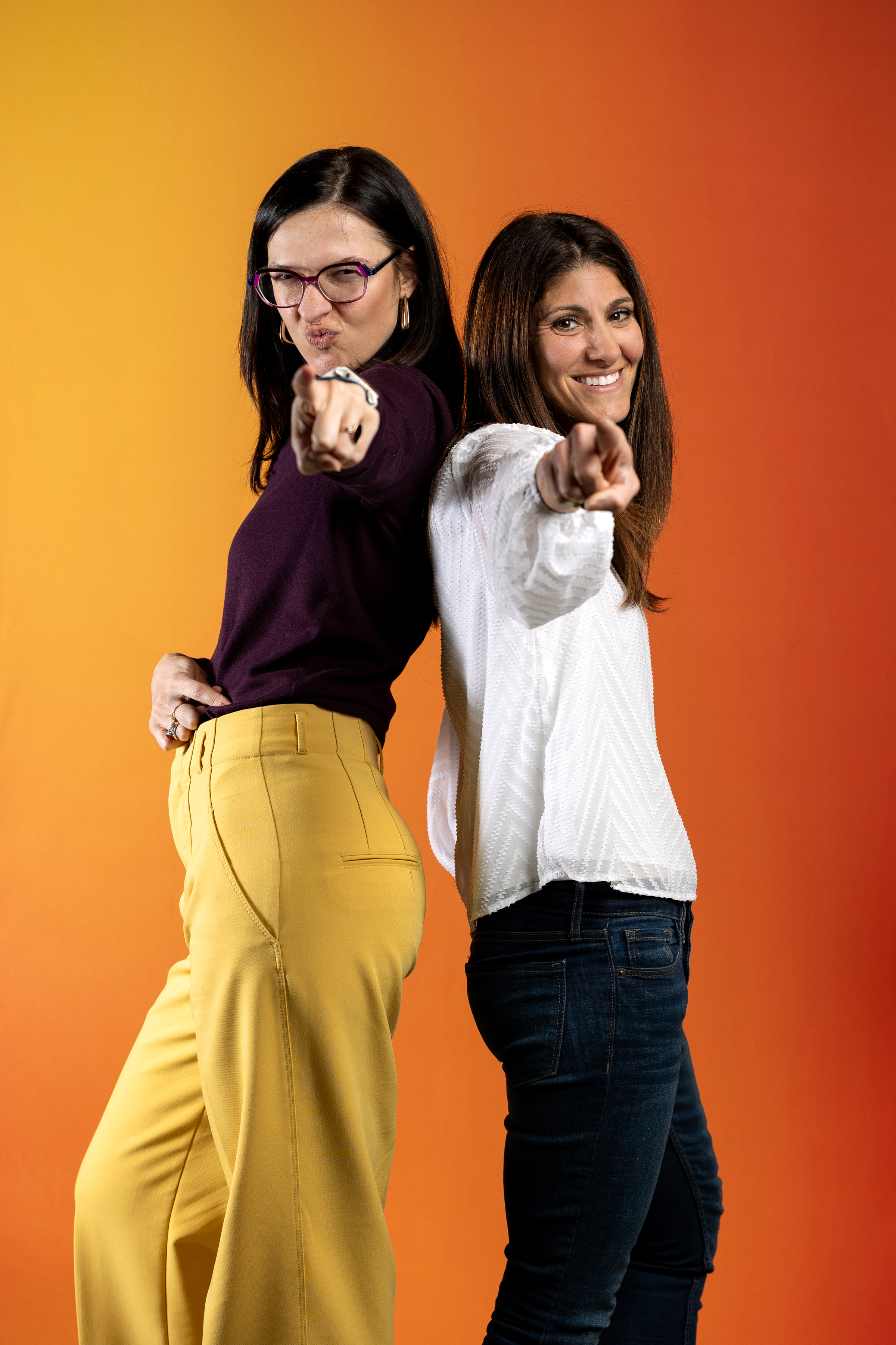 Two smiling employees posing with fingers pointed to the camera