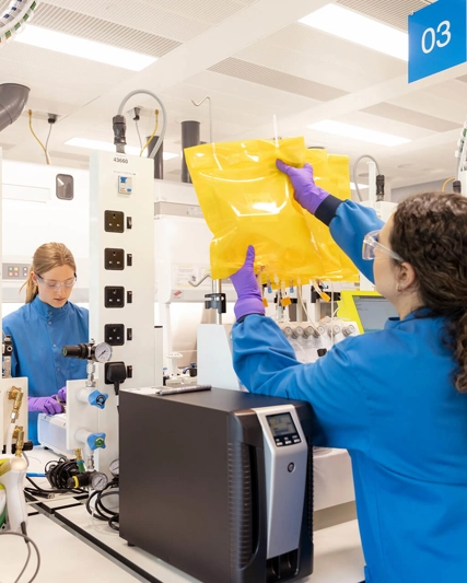 Scientists in protective gear working in the cell and gene therapy lab. They are setting up prodigy