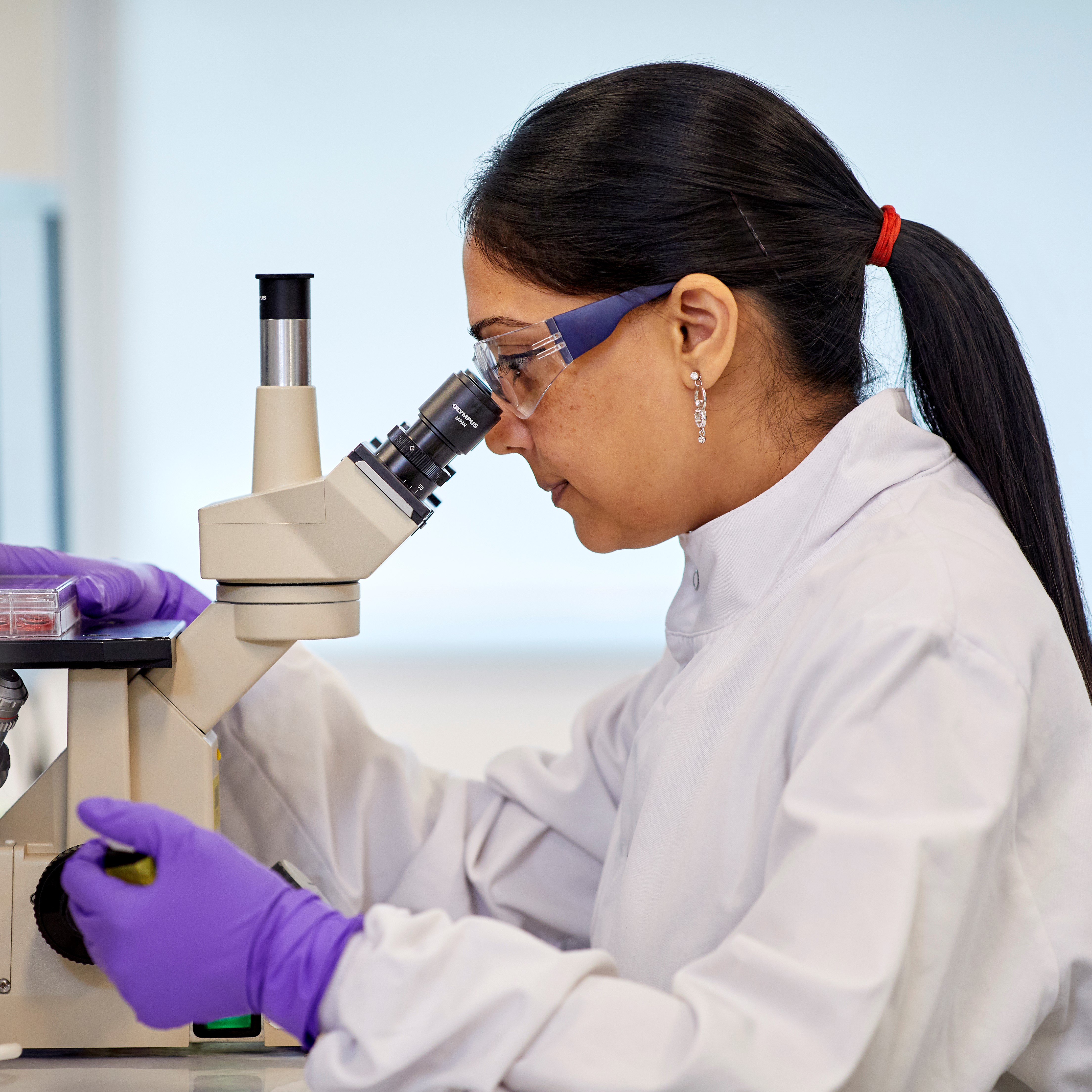 Female scientist looking at microscope. 