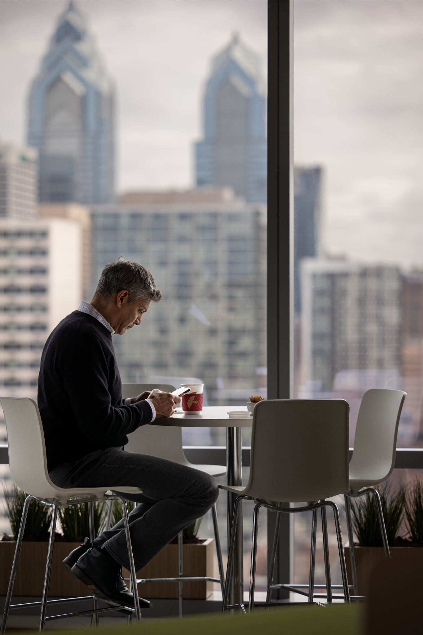 FMC employee sitting in the office with the view of the Philadelphia skyline behind him