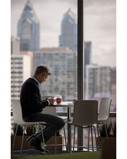 FMC employee sitting in the office with the view of the Philadelphia skyline behind him