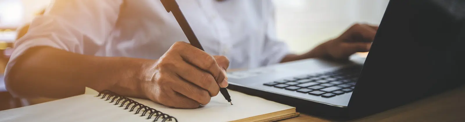 hand holding pen writing in notebook