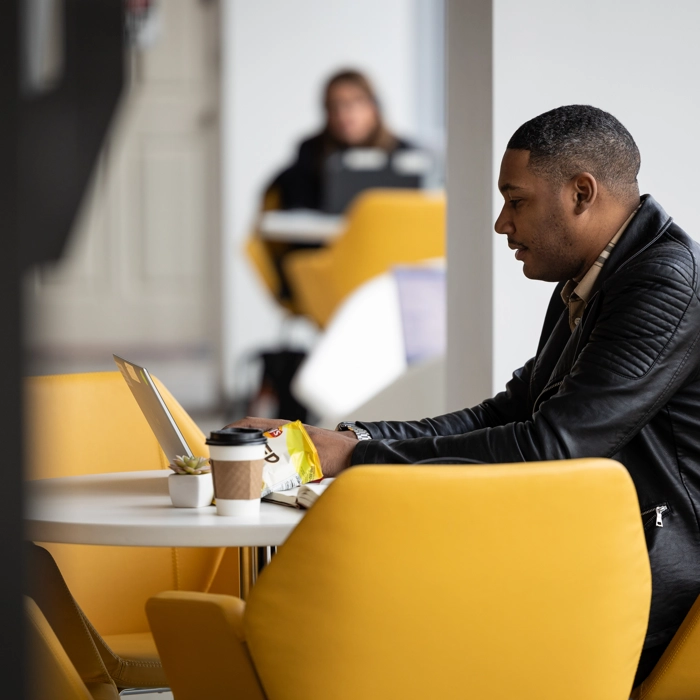 An employee working on his laptop in the office cafe