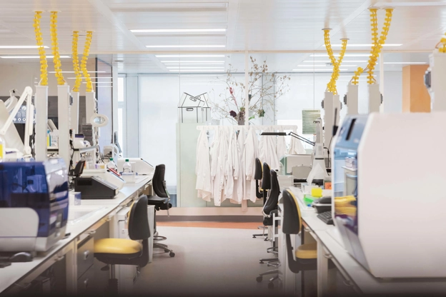 Lab desks and chairs with lab coats hanging in the background