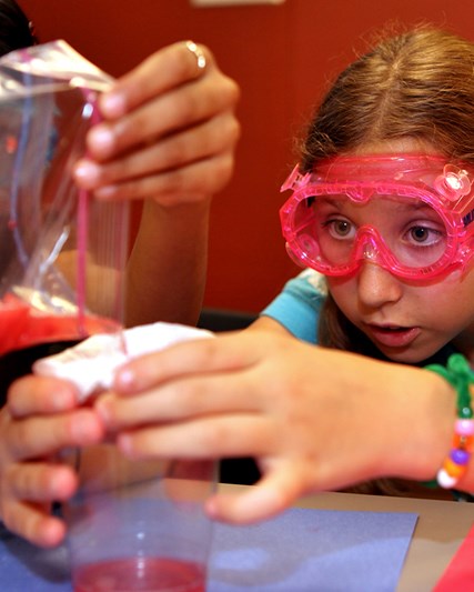 Young girl wearing protective googles working on a science experiment