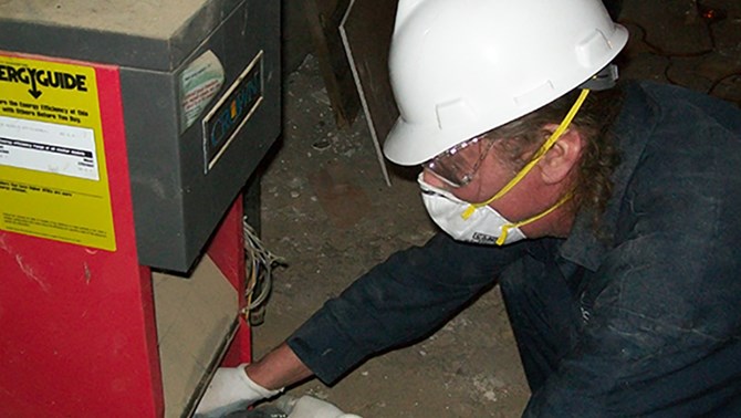 Person in white hardhat working on a heater
