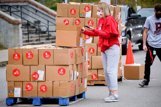 Volunteer wearing a mask adding labels to boxes of supplies on a palette