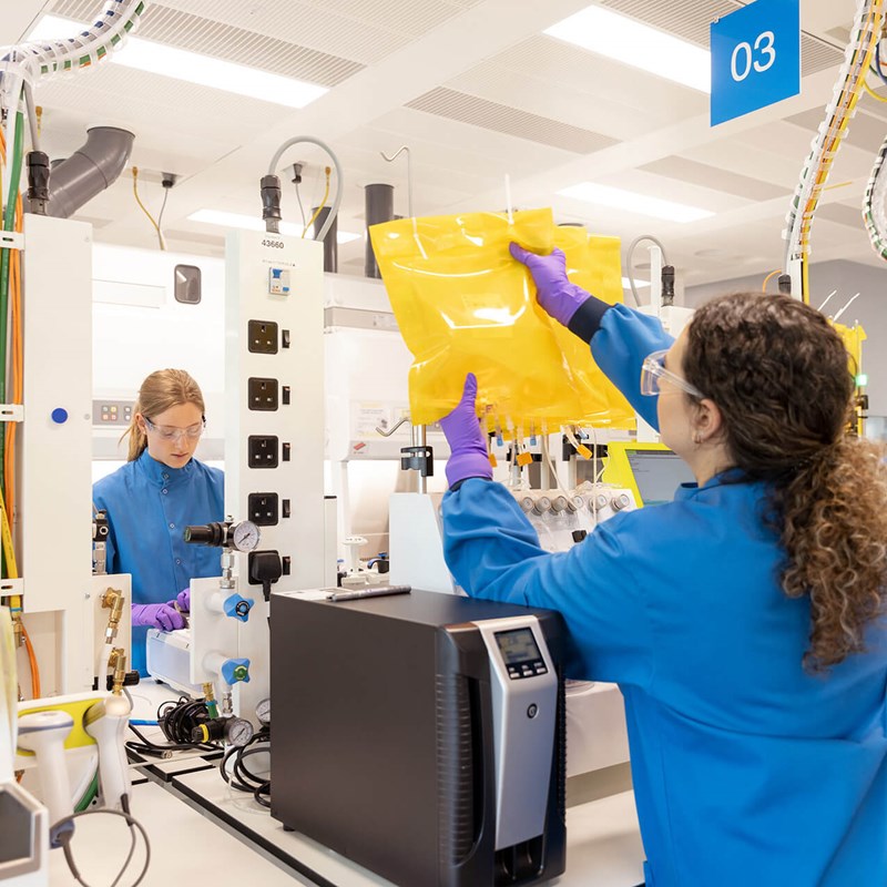 Scientists in protective gear working in the cell and gene therapy lab. They are setting up prodigy