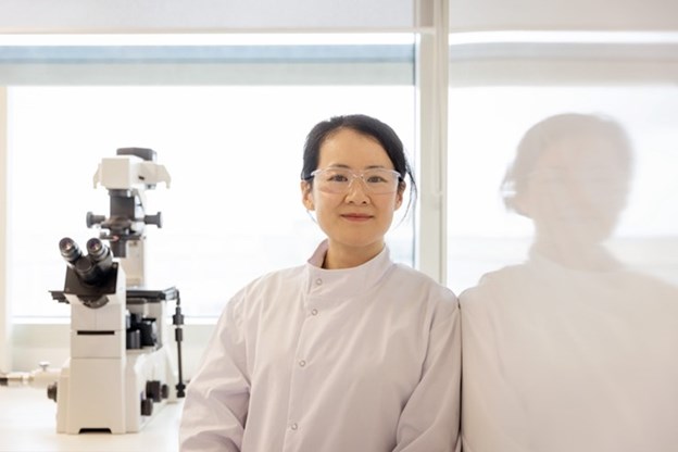 Female scientist standing by telescope. 