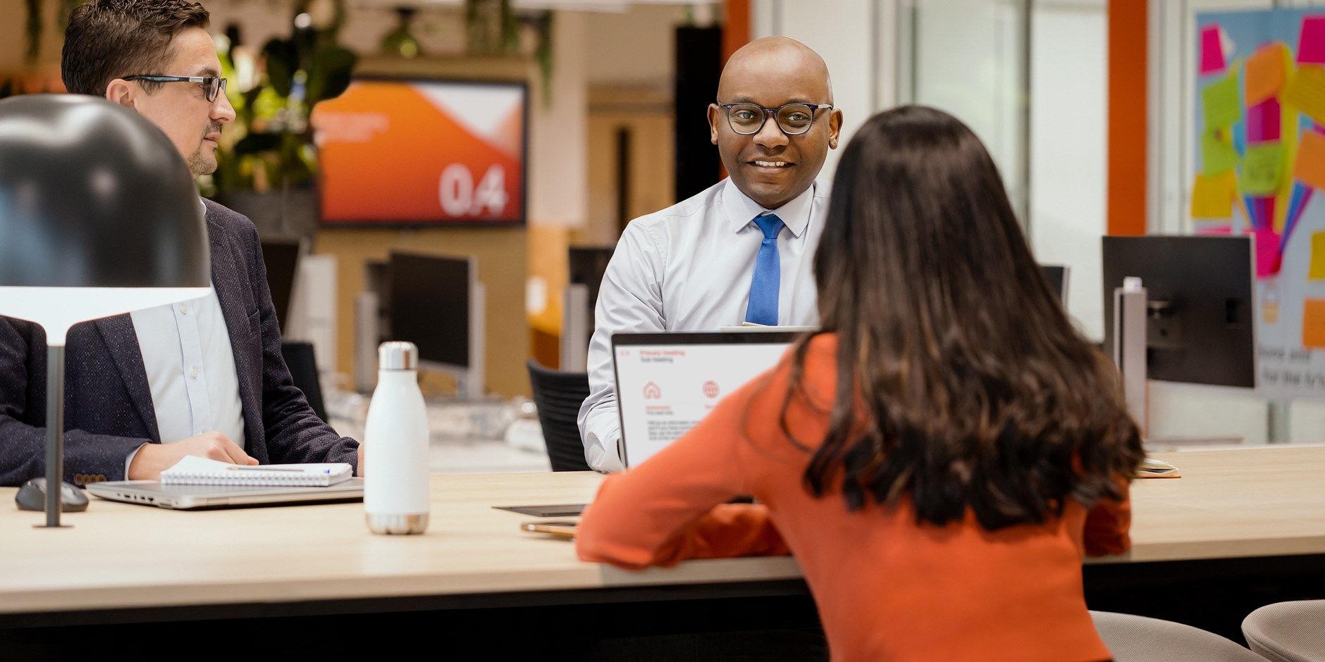 Three people collaborating at a table in an open workspace