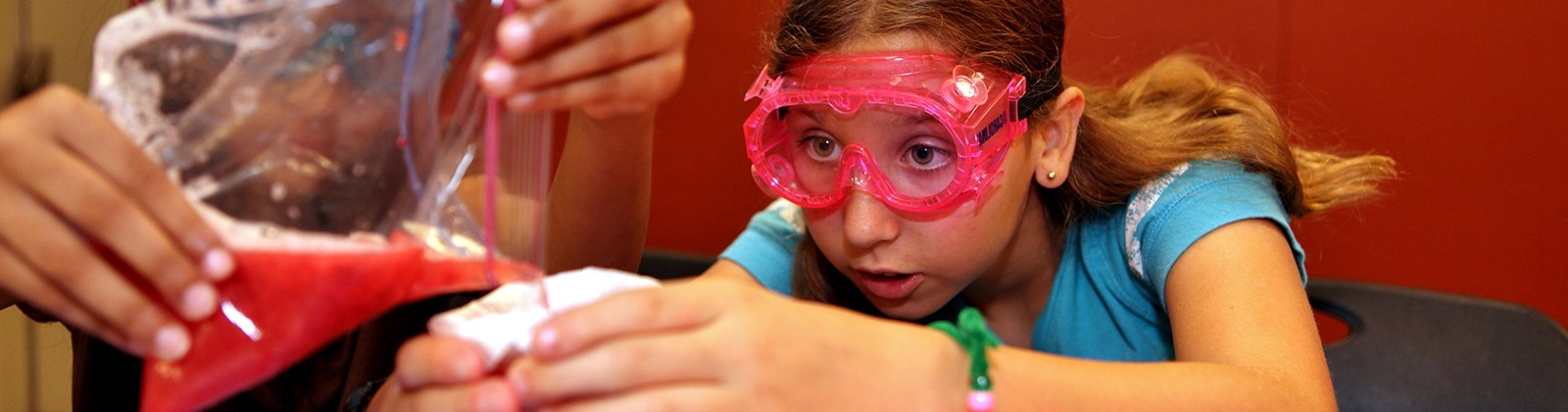 Young girl wearing protective googles working on a science experiment