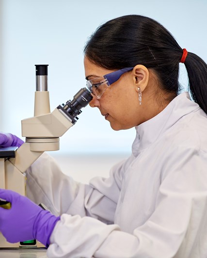 Female scientist looking at microscope. 