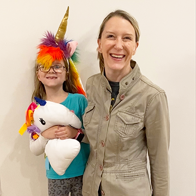 Child in a unicorn costume standing with her mother
