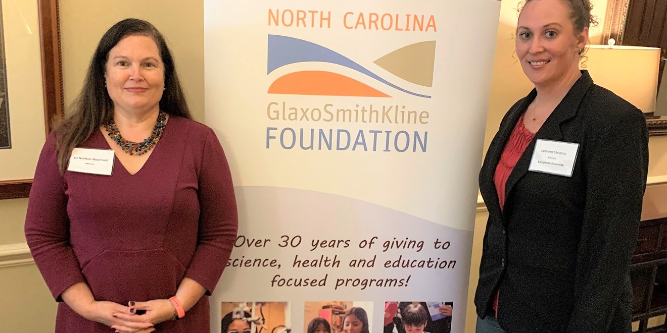two females standing in front of the NC GSK foundation sign.