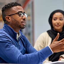 A black male employee and black female employee in the office having a discussion. 