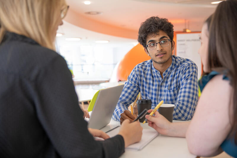 A man in a blue shirt talking to three colleagues 