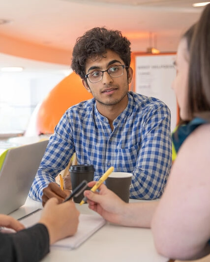 A man in a blue shirt talking to three colleagues
