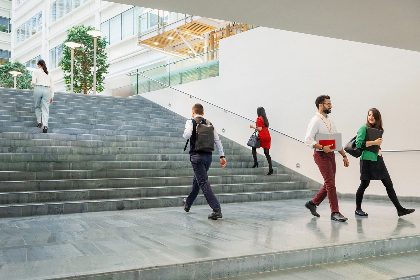 Several colleagues walking in an open space near a wide stairwell 