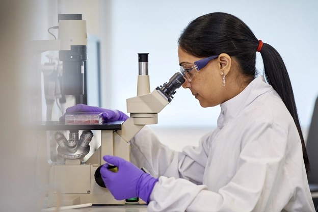 scientist looking through microscope.