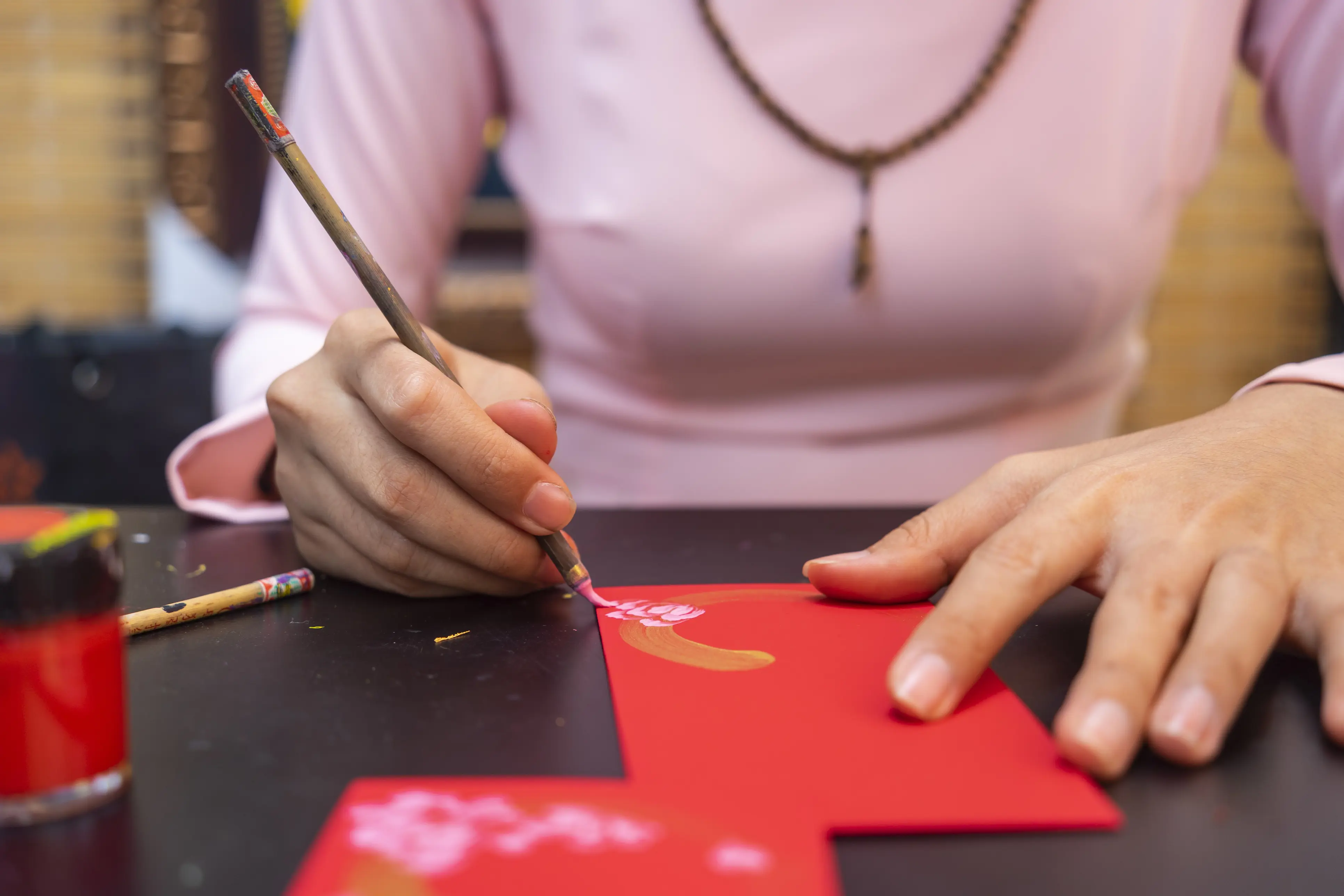hands painting on a red envelope.