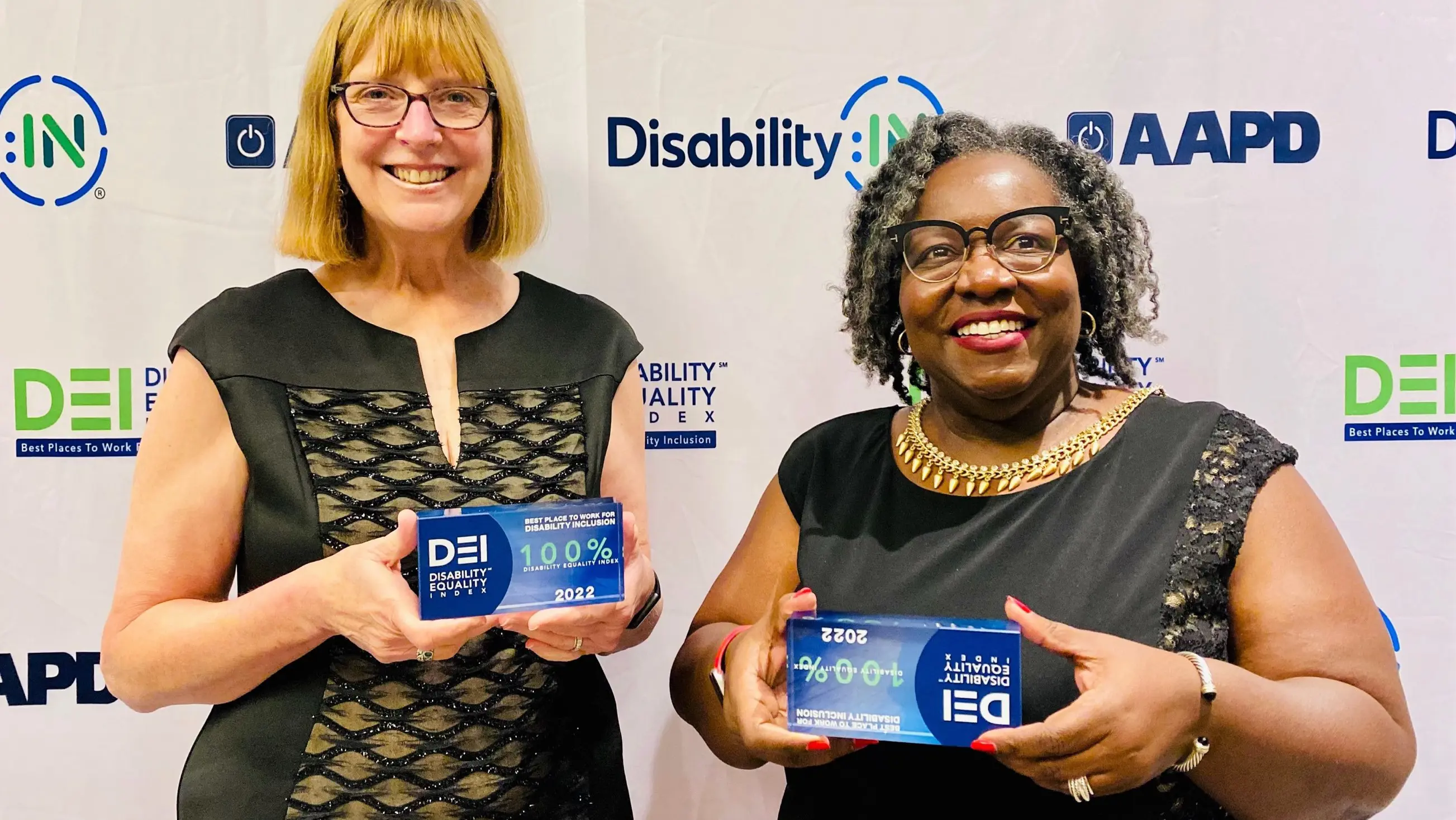 two females taking a photo with an award.