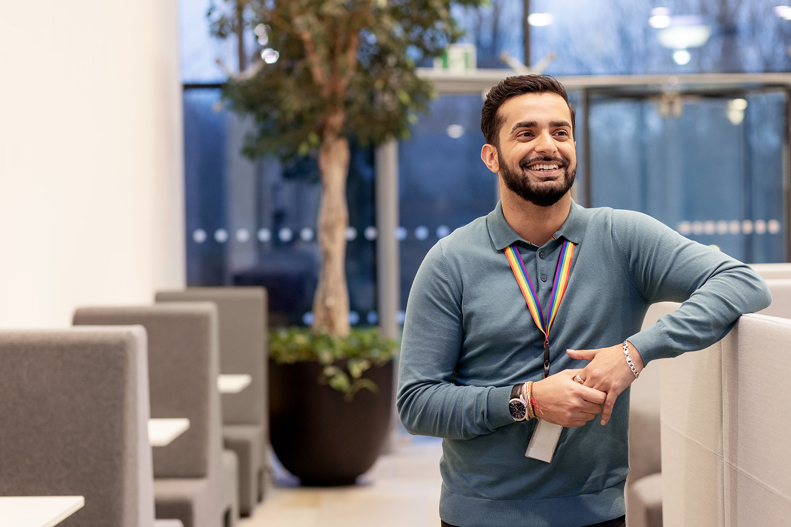 Man with beard and blue shirt smiling at camera in an office lobby 