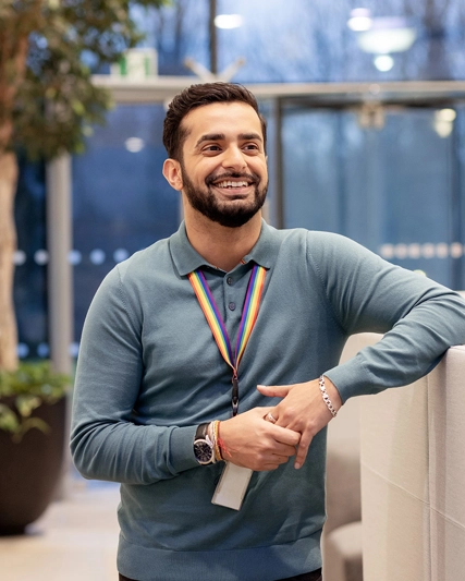 Man with beard and blue shirt smiling at camera in an office lobby