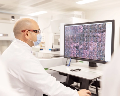 Scientist at a computer monitor looking at 3D images in high throughput screening lab