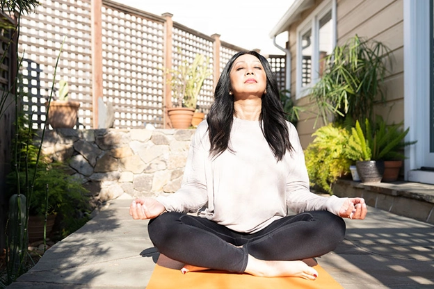 mujer afuera meditando en su patio trasero