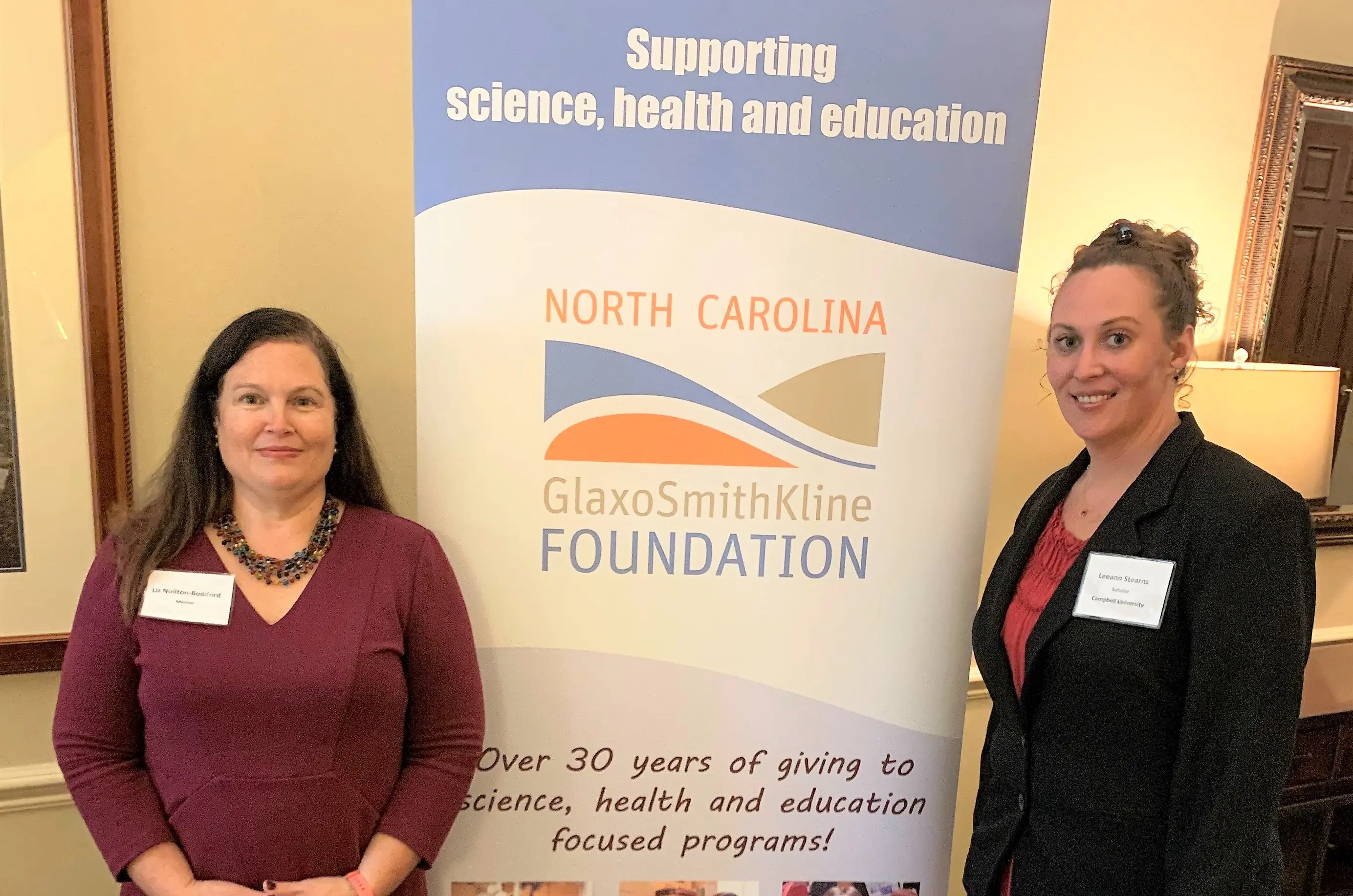 Two females in front of a sign.