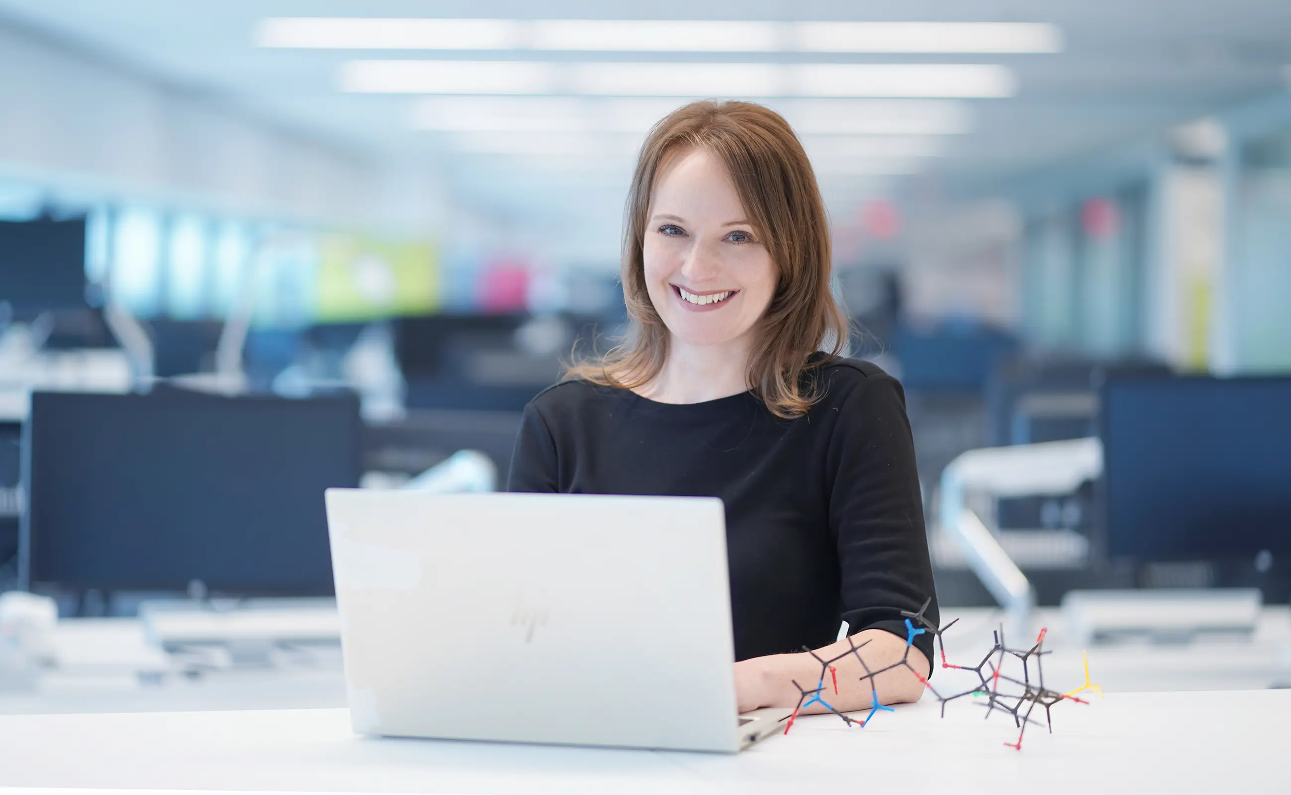 Beth smiling as she looks at the camera using her laptop