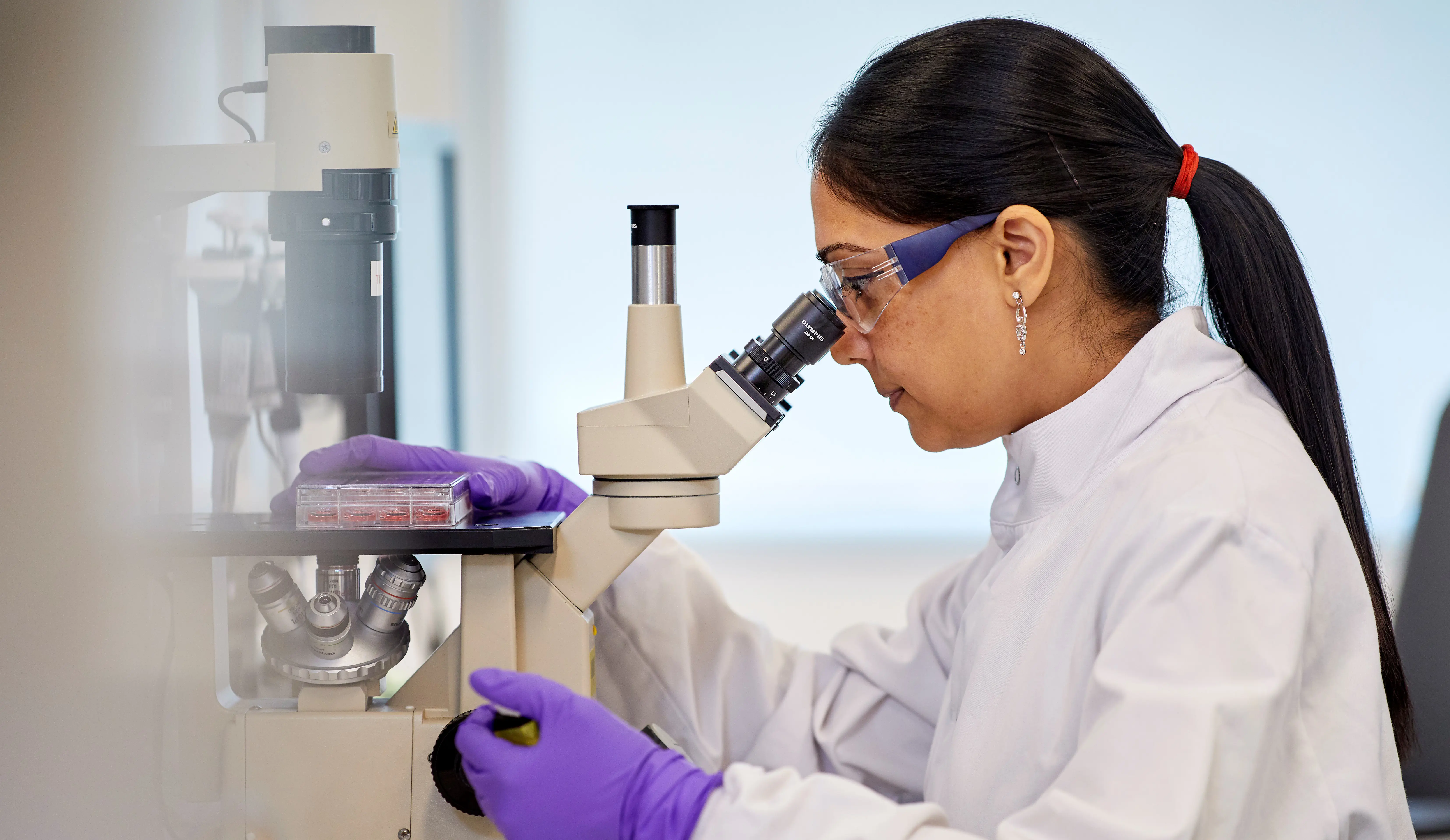 Female scientist looking at microscope. 
