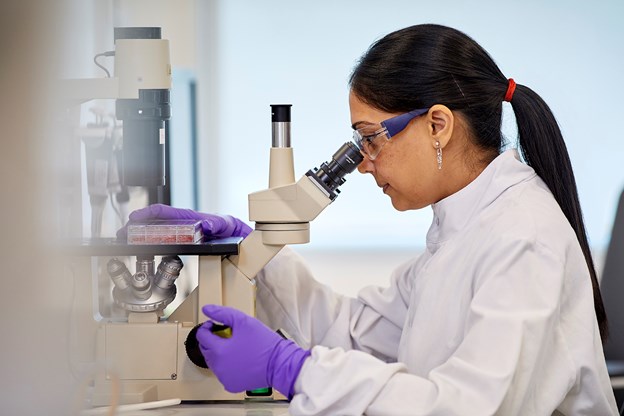 scientist looking through microscope.