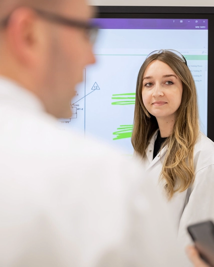 Team member in a white lab coat standing in our quality lab